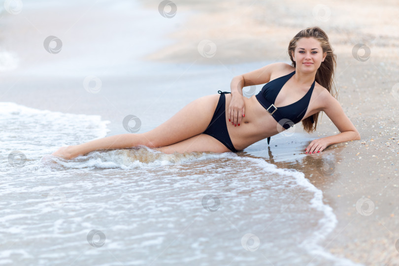 Скачать Женщина лежит на пляже в черном бикини фотосток Ozero