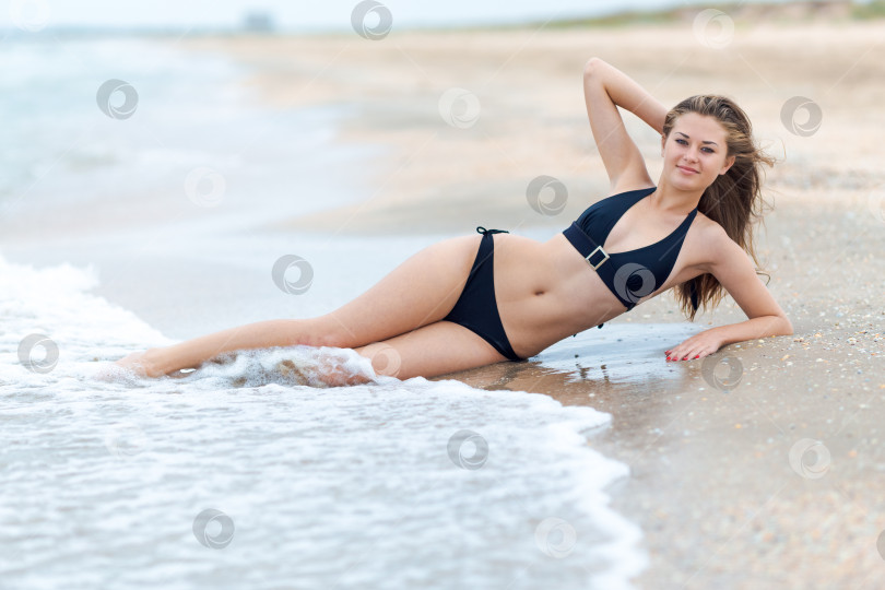 Скачать Женщина лежит на пляже в черном бикини фотосток Ozero