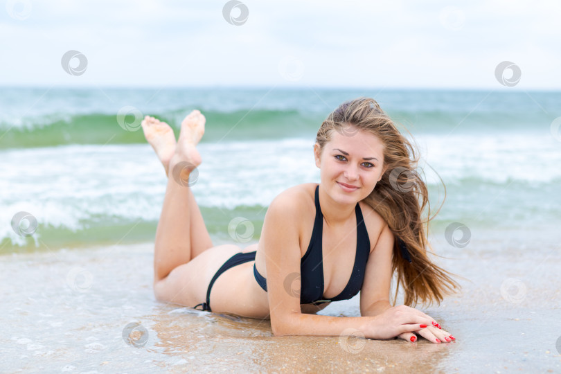 Скачать Женщина лежит на пляже в черном бикини фотосток Ozero