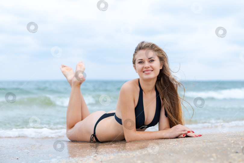 Скачать Женщина лежит на пляже в черном бикини фотосток Ozero