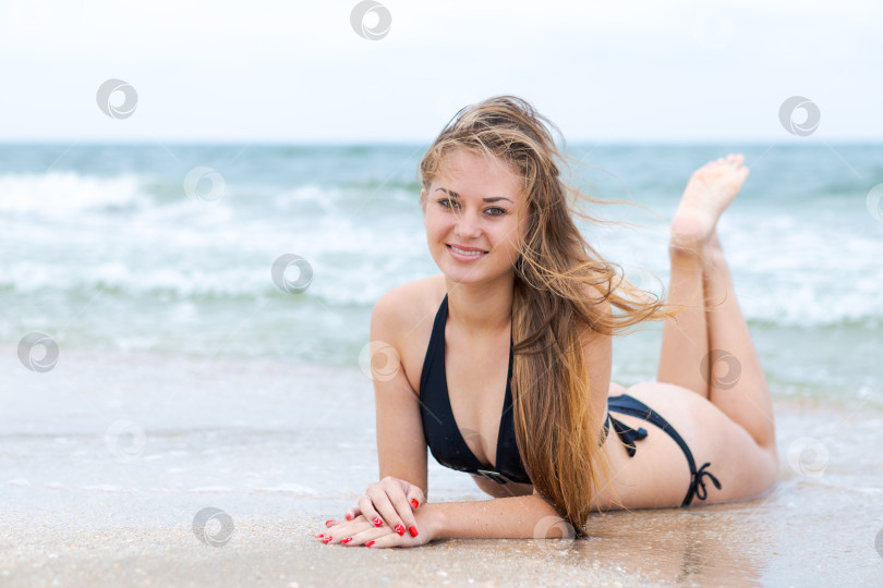 Скачать Женщина лежит на пляже в черном бикини фотосток Ozero