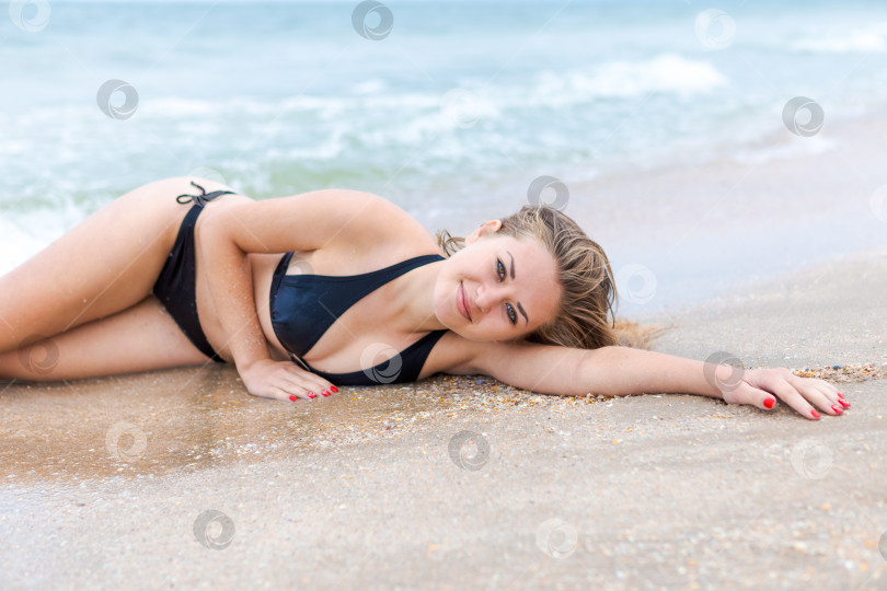 Скачать Женщина лежит на пляже в черном бикини фотосток Ozero