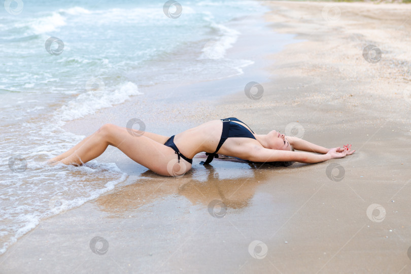 Скачать Женщина лежит на пляже в черном бикини фотосток Ozero