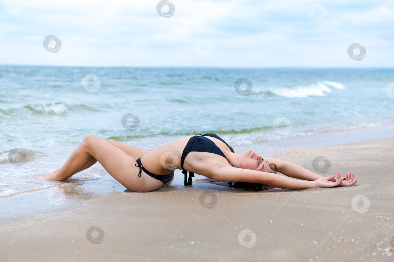 Скачать Женщина лежит на пляже в черном бикини фотосток Ozero