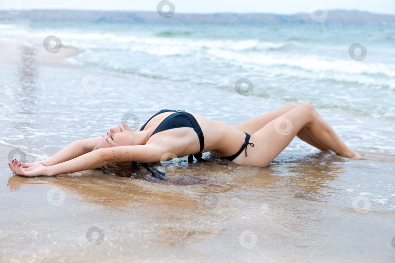 Скачать Женщина лежит на пляже в черном бикини фотосток Ozero