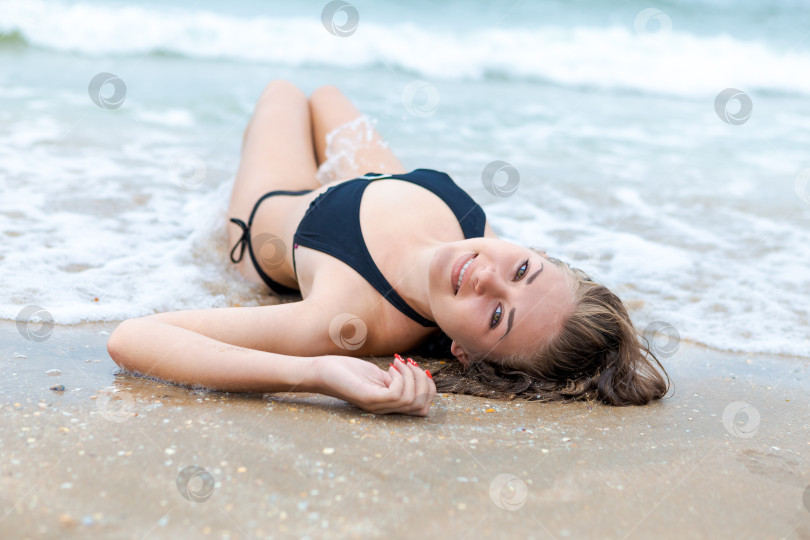 Скачать Женщина лежит на пляже в черном бикини фотосток Ozero