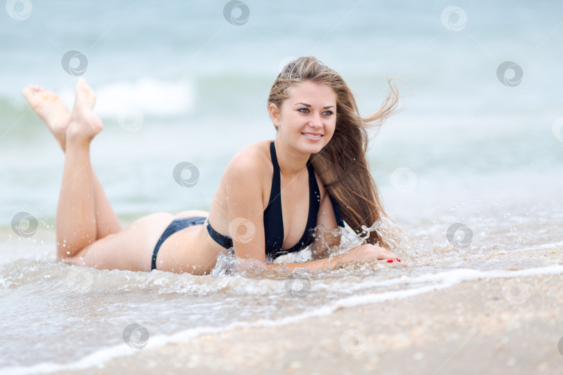 Скачать Женщина лежит на пляже в черном бикини фотосток Ozero