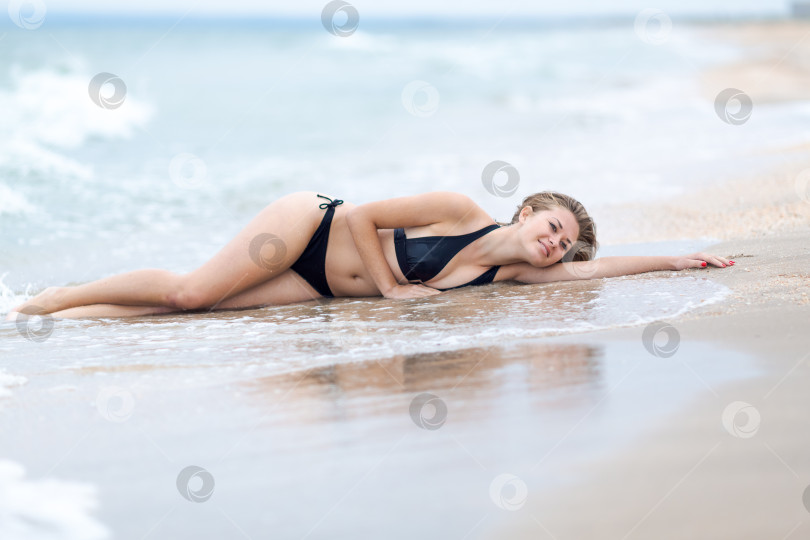 Скачать Женщина лежит на пляже в черном бикини фотосток Ozero