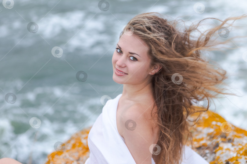 Скачать Женщина с длинными волосами сидит на камне у воды фотосток Ozero