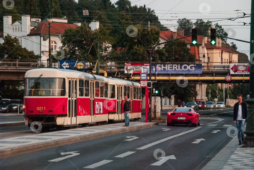 Скачать Красный трамвай и спортивный автомобиль на городской улице с людьми и светофорами фотосток Ozero