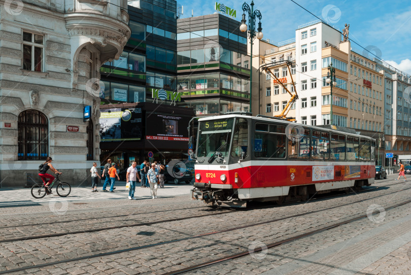 Скачать Исторический трамвай на оживленной улице европейского города с пешеходами и велосипедистами фотосток Ozero
