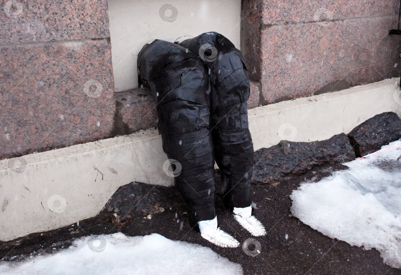 Скачать Художественная инсталляция из штанов в снегу у бетонной стены фотосток Ozero