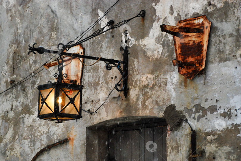 Скачать Старинный железный фонарь, висящий на выветренной деревенской стене с облупившейся краской фотосток Ozero