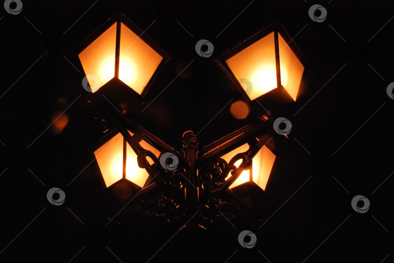 Скачать Старинный уличный фонарь, тепло светящийся ночью фотосток Ozero