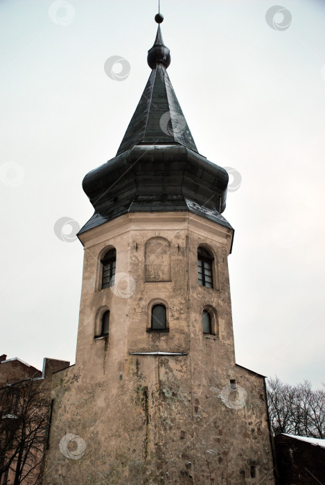 Скачать Историческая каменная башня с темным шпилем на фоне облачного неба фотосток Ozero