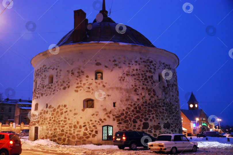 Скачать Историческая каменная башня и транспортные средства в зимней ночной сцене фотосток Ozero