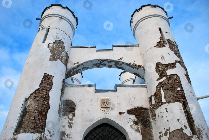 Скачать Исторические белые ворота замка с выветрившимися башнями на фоне голубого неба фотосток Ozero