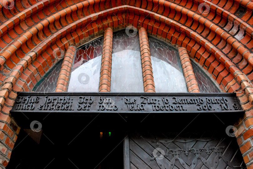 Скачать Готический кирпичный вход в церковь с арочными окнами и надписью на немецком языке фотосток Ozero