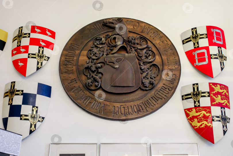 Скачать Исторический средневековый герб изображен на белой стене с разноцветными щитами фотосток Ozero