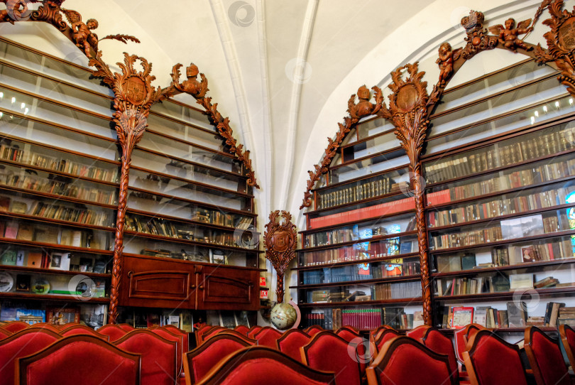 Скачать Богато украшенный интерьер библиотеки с деревянными книжными полками и красными стульями фотосток Ozero