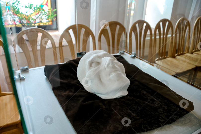 Скачать Историческая белая посмертная маска в стеклянной витрине на фоне витражного стекла фотосток Ozero