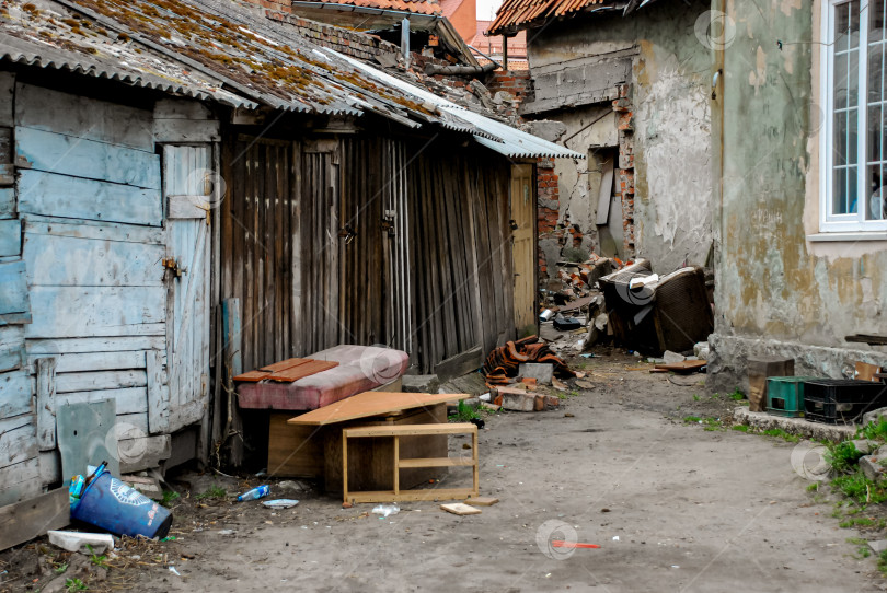 Скачать Обветшалая городская аллея со старыми деревянными сараями и мусором фотосток Ozero