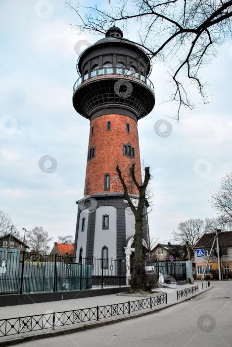 Скачать Историческая водонапорная башня из кирпича и железа на фоне облачного неба в городской обстановке фотосток Ozero