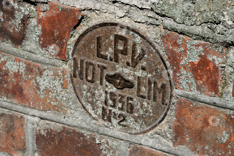 Скачать Ржавая круглая металлическая пластина на выветренной кирпичной стене, покрытой мхом и лишайником фотосток Ozero