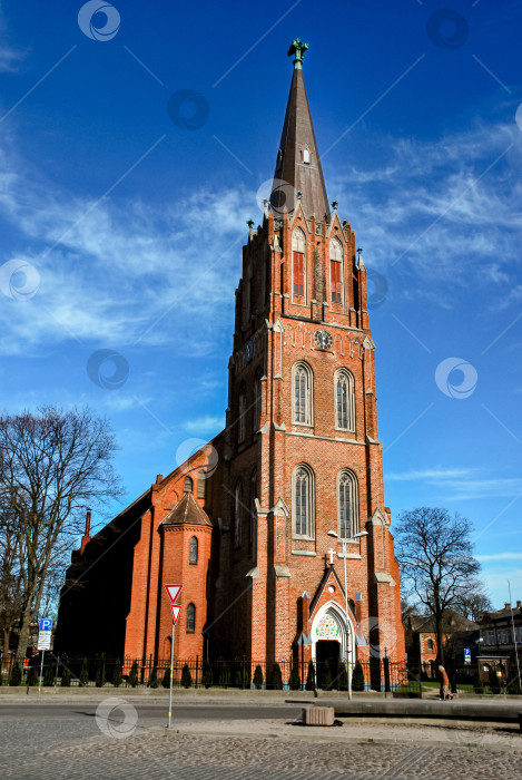 Скачать Кирпичная церковь в стиле готического возрождения с башней на фоне голубого неба фотосток Ozero