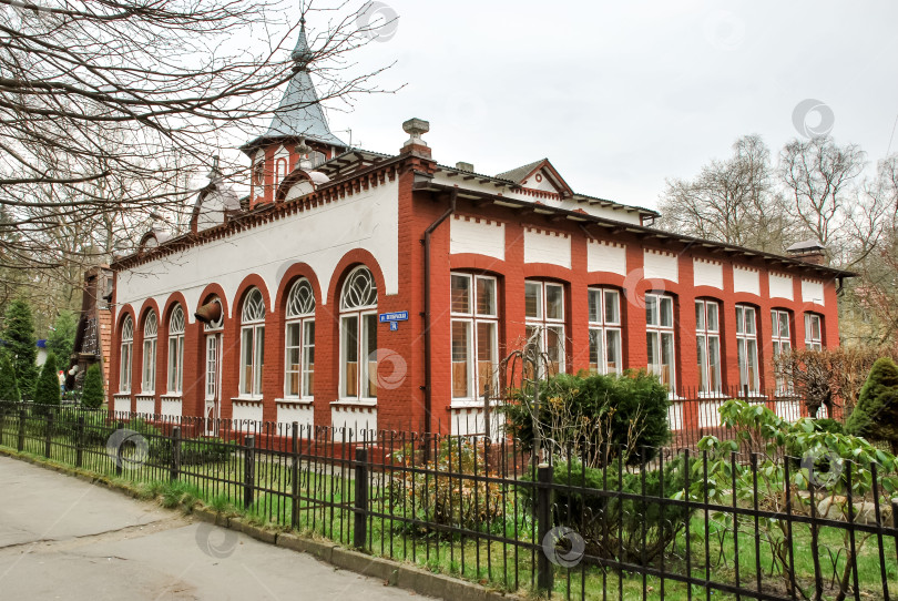 Скачать Историческое здание из красного кирпича с арочными окнами и башней в окружении парка фотосток Ozero