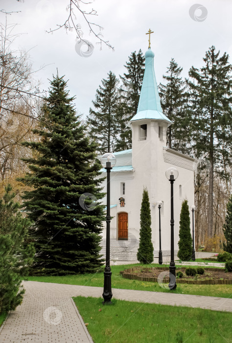 Скачать Тихая белая часовня, окруженная деревьями, с голубым шпилем в безмятежном лесу фотосток Ozero