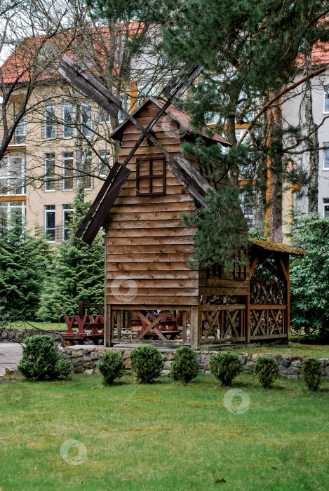 Скачать Деревенская деревянная ветряная мельница в пышном саду с местом для пикника фотосток Ozero