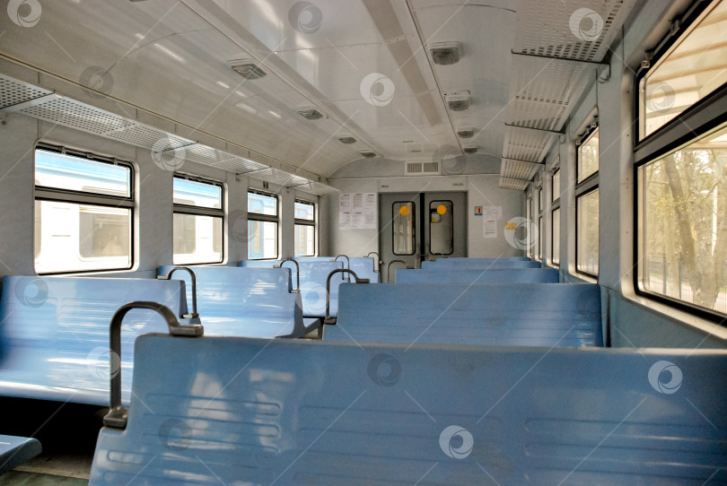 Скачать Пустой вагон поезда с голубыми сиденьями и залитыми солнцем окнами фотосток Ozero