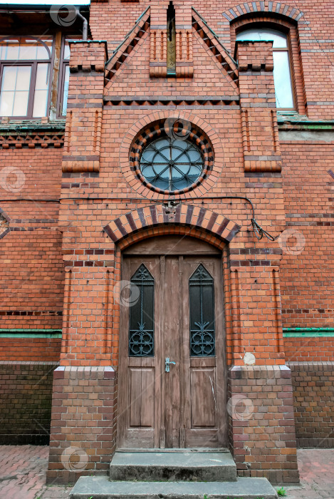 Скачать Исторический фасад здания из красного кирпича с деревянными дверями и круглым окном фотосток Ozero