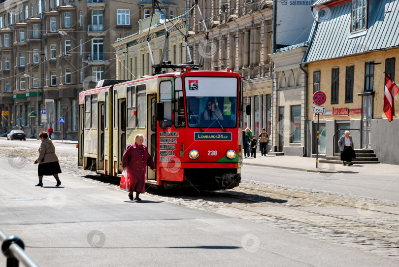 Скачать Красный трамвай на городской улице со зрелыми кавказскими женщинами-пешеходами фотосток Ozero