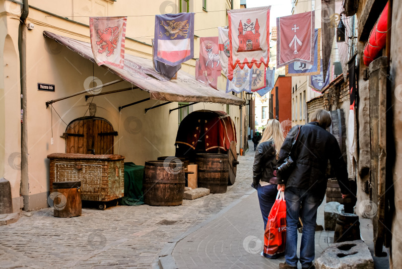 Скачать Историческая европейская аллея со старинными рыночными прилавками и разноцветными флагами фотосток Ozero