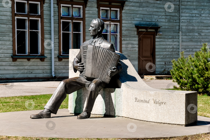 Скачать Бронзовая статуя аккордеониста на скамейке перед историческим зданием фотосток Ozero
