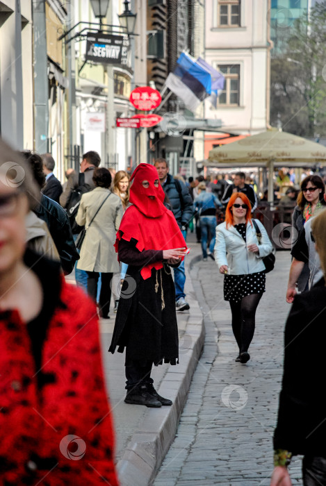 Скачать Человек, одетый в красный капюшон, на оживленной европейской улице с разнообразной толпой фотосток Ozero