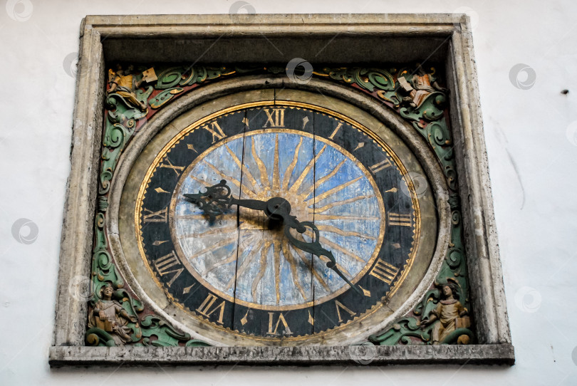 Скачать Старинные башенные часы с римскими цифрами и богато украшенной рамкой на белой стене фотосток Ozero