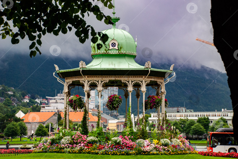 Скачать Богато украшенная беседка в цветущем парке на фоне гор в пасмурный день фотосток Ozero