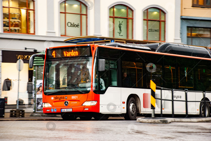 Скачать Красно-белый городской автобус на улице возле магазинов в скандинавском городке фотосток Ozero