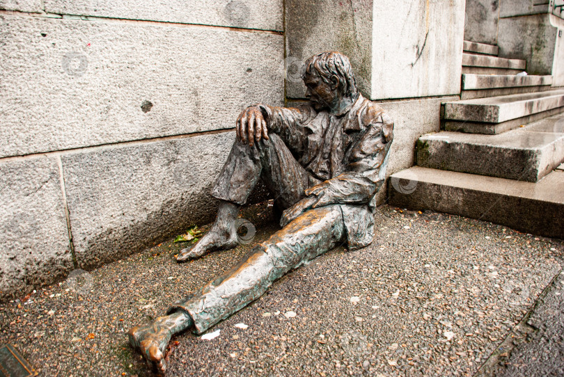 Скачать Бронзовая статуя сидящего в раздумье человека на городской улице фотосток Ozero