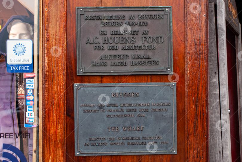 Скачать Исторические таблички на деревянных стенах в Бергене, подчеркивающие архитектурное наследие фотосток Ozero