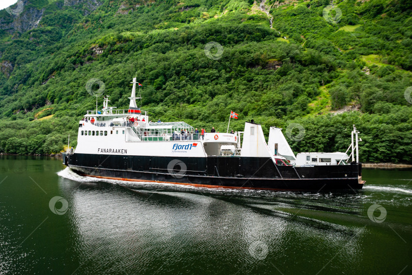 Скачать Живописный паромный причал в норвежском фьорде, окруженный пышной растительностью и величественными холмами фотосток Ozero