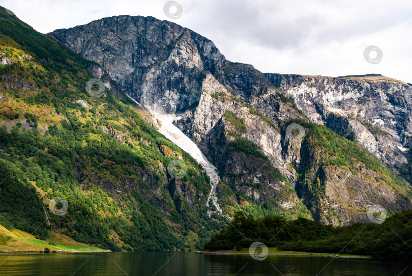 Скачать Величественный горный пейзаж с пышной зеленью и водопадом фотосток Ozero