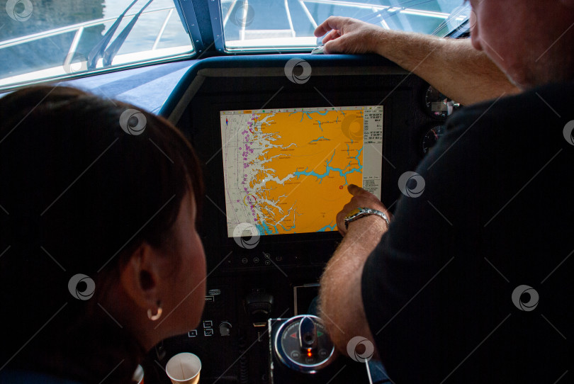 Скачать Навигационные технологии на лодке, когда взрослые мужчины и женщины рассматривают цифровую карту на дисплее фотосток Ozero