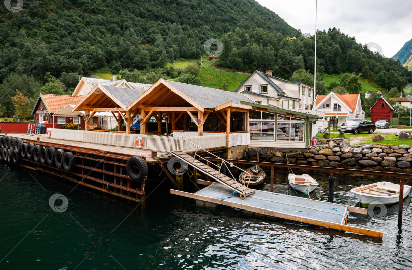 Скачать Очаровательный прибрежный пирс с деревянным павильоном и лодками в живописной горной деревне фотосток Ozero