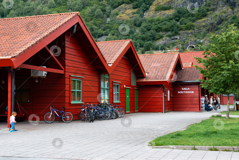Скачать Красные деревянные здания с велосипедами рядом с горами в живописной норвежской деревне фотосток Ozero