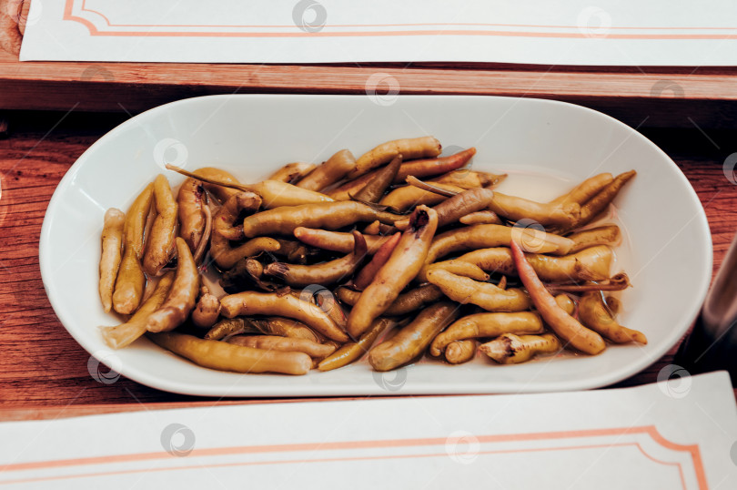 Скачать Острый, пикантный маринованный перец Халапеньо Чили в белой тарелке на столе в ресторане фотосток Ozero