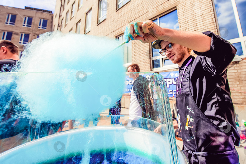 Скачать Москва, Россия, 2 мая 2021 года, продавец сматывает голубую сахарную вату в киоске уличной еды фотосток Ozero